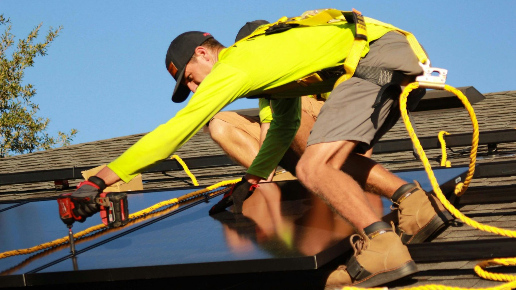 Close view of an installer fastening a solar panel with a power drill